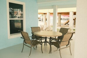 Un coin repas avec une table ronde et six chaises, une fenêtre donnant sur l’extérieur et un mur de couleur bleu clair.
