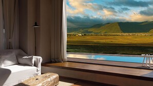 A modern room with a large window overlooking a scenic landscape. - Liz's heart is in the sky (Deqin)