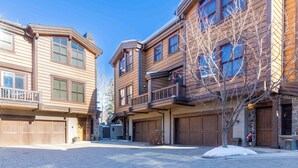 A multi-story building with a brick-paved courtyard, wooden balconies, and large garage doors. - SkiView Luxury Townhome - Steps to Ketchum + Skiing, Dog-Friendly! (Ketchum)