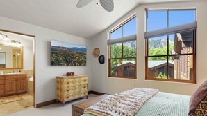 A bedroom with a large window, a bed, a dresser, a mirror, and a painting of a landscape. - SkiView Luxury Townhome - Steps to Ketchum + Skiing, Dog-Friendly! (Ketchum)