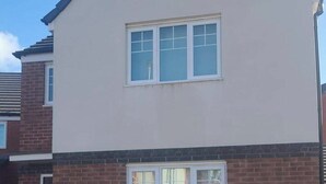 A two-story residential building with a beige facade and a brick base. - House - Sleeps 8 - Parking - Station Close (Wolverhampton)