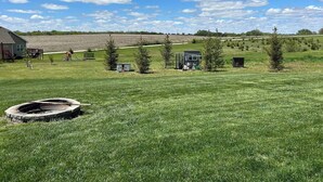 Un campo erboso con un piccolo deposito, una struttura giochi e una casa sullo sfondo.