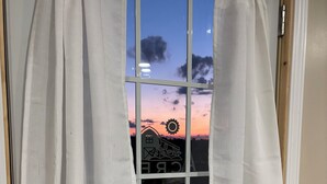Una porta con finestra che mostra una vista al tramonto, una maniglia in metallo e un portasciugamani.