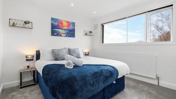 Un dormitorio con una cama grande, una ventana y un cuadro en la pared.
