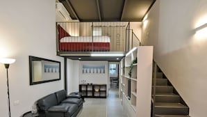 Et moderne hotelværelse med en køjeseng, en sofa, et lille bord, et spejl og en trappe.