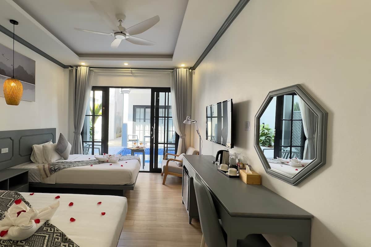 A hotel room with a bed, a desk, a chair, a ceiling fan, a TV, and a large window.