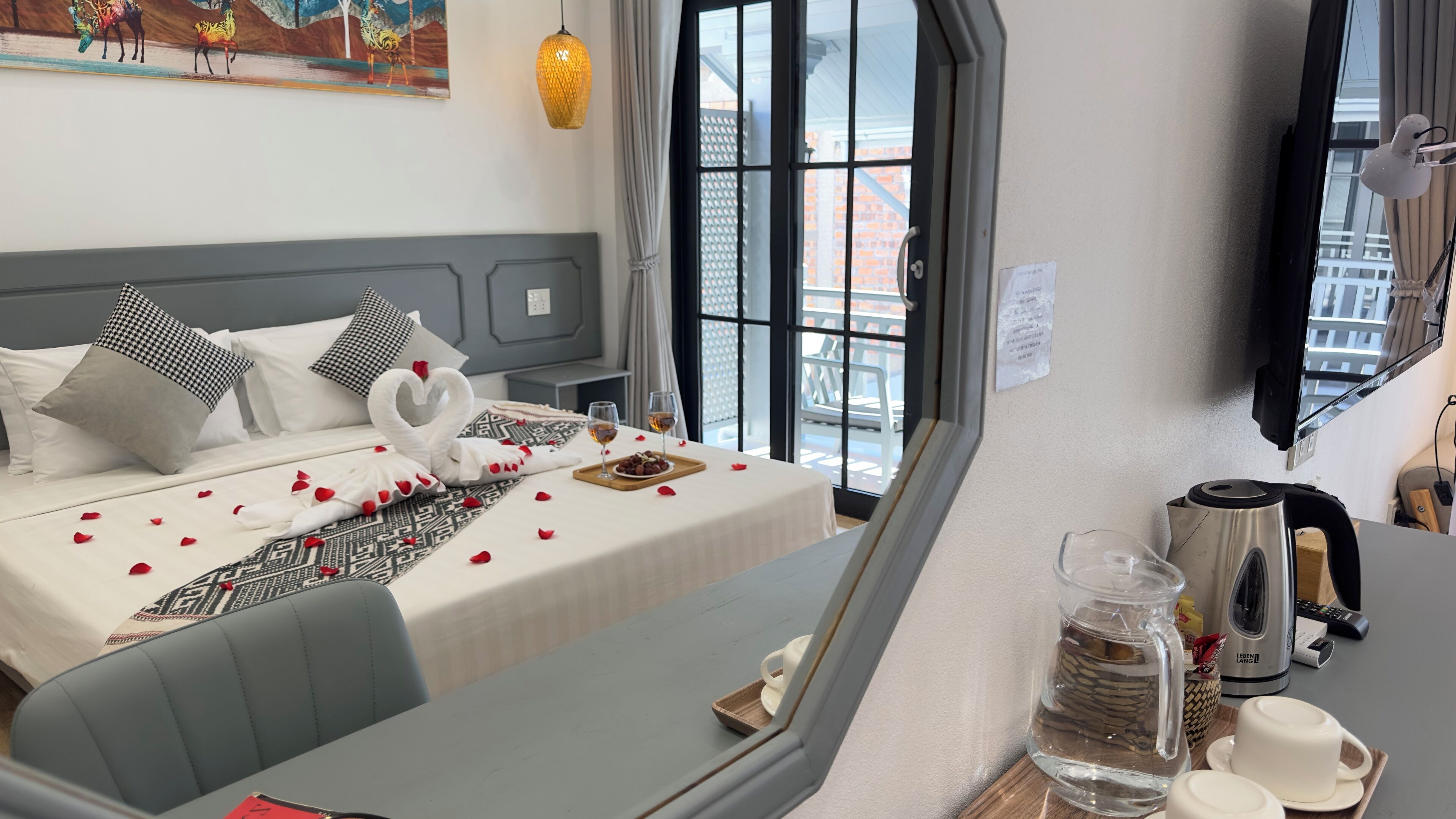 Een hotelkamer met een bed, een tafel met waterkoker en kopjes, en uitzicht op het omliggende landschap.