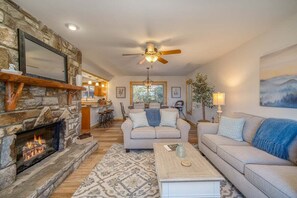 A living room with a stone fireplace, a ceiling fan, a sofa, and a coffee table.