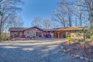 A two-story house with a stone facade, a covered porch, and a gravel driveway.