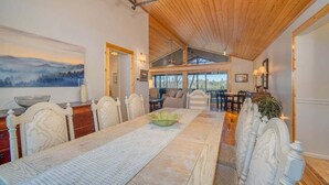A dining area with a long table, chairs, and a view of the outdoors. - Treetop Retreat in Connestee Falls (Brevard)