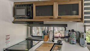 A compact kitchen with a microwave, stove, and coffee maker.