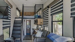 A compact living space with a bunk bed, kitchenette, and a sofa.