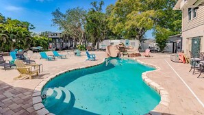 A swimming pool with lounge chairs and a covered area.