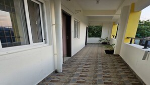 A corridor with tiled flooring, white walls, and a yellow accent wall. - Pondy Pleasant Stay (Puducherry)