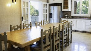 Un comedor con mesa y sillas de madera, un refrigerador y una encimera de cocina.