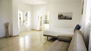 Una habitación amplia con una cama grande, un sofá y un cuadro en la pared.