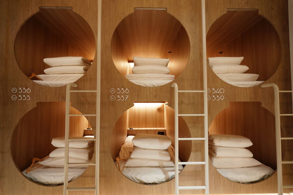 A hotel room with circular wooden bunk beds, each with a ladder and multiple pillows.