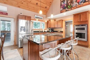 Una cucina moderna con mobili in legno, elettrodomestici in acciaio inossidabile e un'isola centrale con sgabelli da bar.