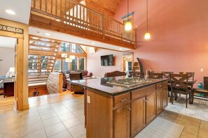 Cucina spaziosa con isola grande, soffitto in legno e vista su una foresta.