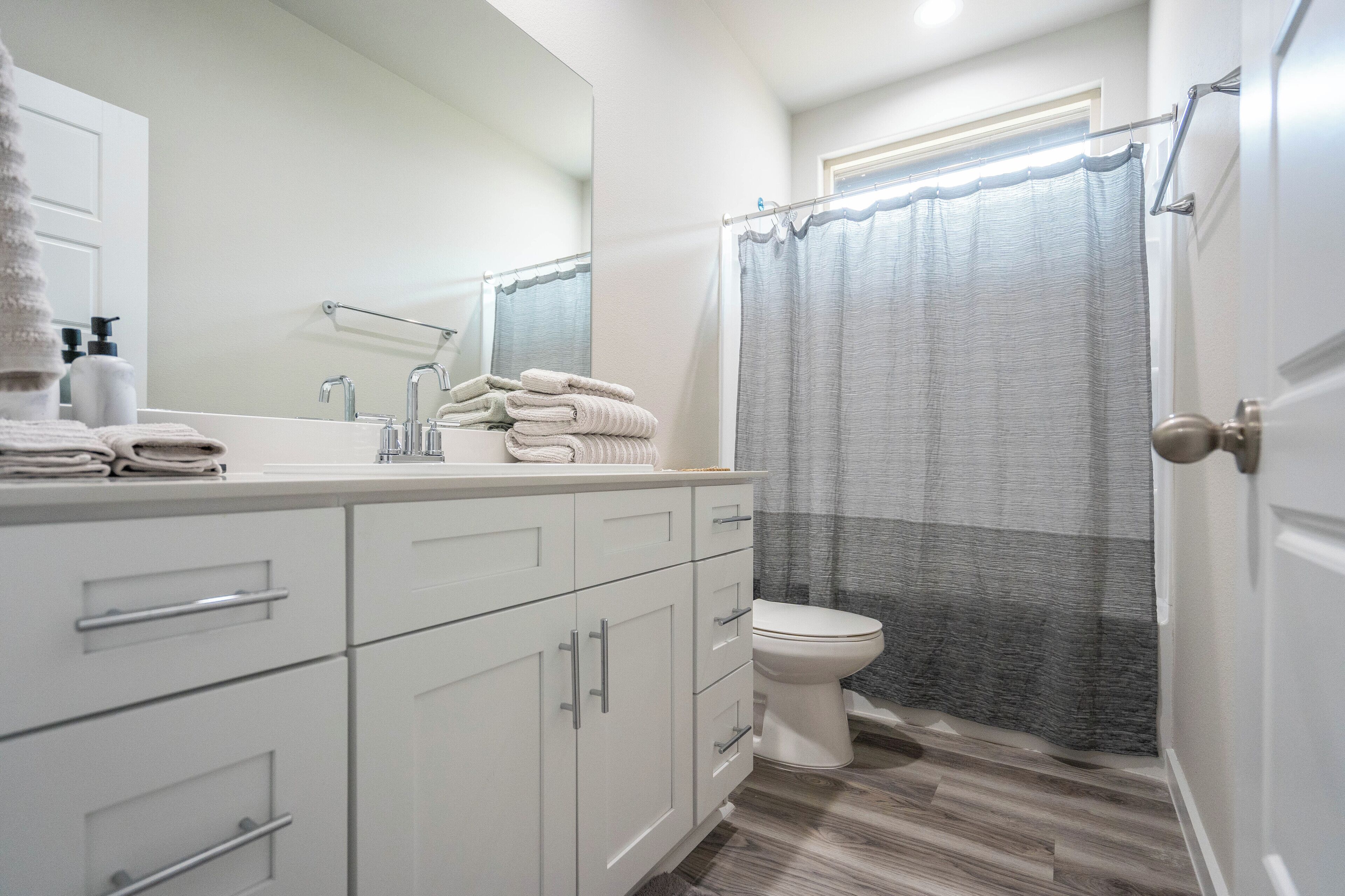 A modern bathroom with a white vanity, a toilet, and a shower curtain.