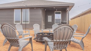 Uma casa com varanda coberta, com cadeiras Adirondack e uma lareira.