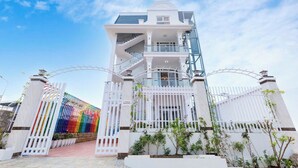 A multi-story building with a white facade, a central staircase, and a gated entrance. - Japan Villa Homestay ByTheHill (Lam Vien - Da Lat)