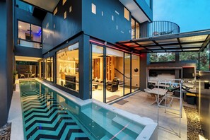 Una casa moderna con piscina, puertas de cristal y zona exterior cubierta.