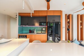 A modern kitchen with wooden cabinets, a black refrigerator, and a teal backsplash. - Beautiful Sea View Full Smart House 3BR (Rawai)