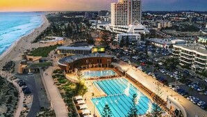 A coastal hotel with a large swimming pool, beachfront access, and a prominent hotel building.