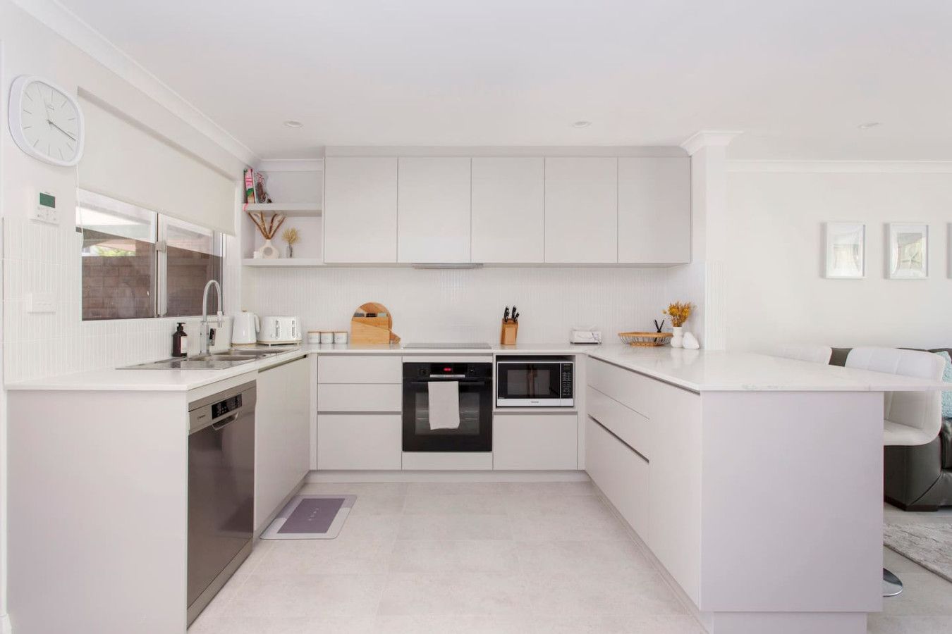 A modern kitchen with white cabinetry, a built-in oven, microwave, and dishwasher.