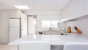 A modern kitchen with white cabinetry, a marble countertop, and a built-in oven. - Maylands Riverside City Retreat (Maylands)