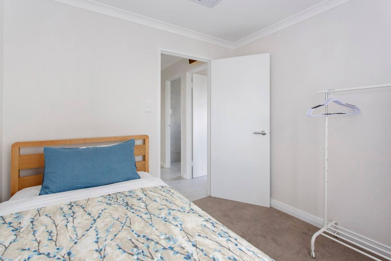A bedroom with a bed, a wardrobe, and a door leading to another room.