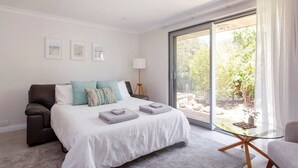 A bedroom with a bed, a chair, a lamp, and a view of the outdoors. - Maylands Riverside City Retreat (Maylands)