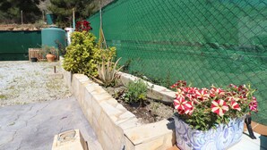 A garden with raised beds, a green fence, and a variety of plants. - 1213 Cortijo del Rey (Frigiliana)