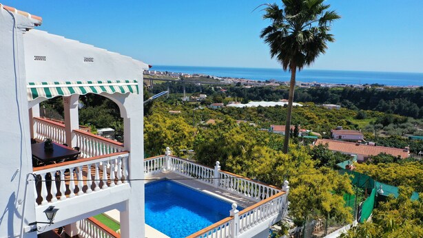 A white building with a pool, a balcony with a white balustrade, and a view of the sea and greenery. - 1213 Cortijo del Rey (Frigiliana)