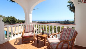 A balcony with two wicker chairs and a small table, overlooking a scenic view of the sea and greenery. - 1213 Cortijo del Rey (Frigiliana)