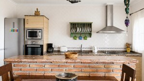 A kitchen with a brick island, a microwave, a stove, a coffee maker, and a hanging light fixture. - 1213 Cortijo del Rey (Frigiliana)