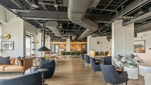 Un salon spacieux et moderne, doté de canapés et de fauteuils en cuir, ainsi que d’un coin repas avec des tables et des chaises.