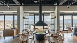 Un intérieur moderne avec un foyer central, un espace salon et de grandes fenêtres offrant une vue sur la ville.