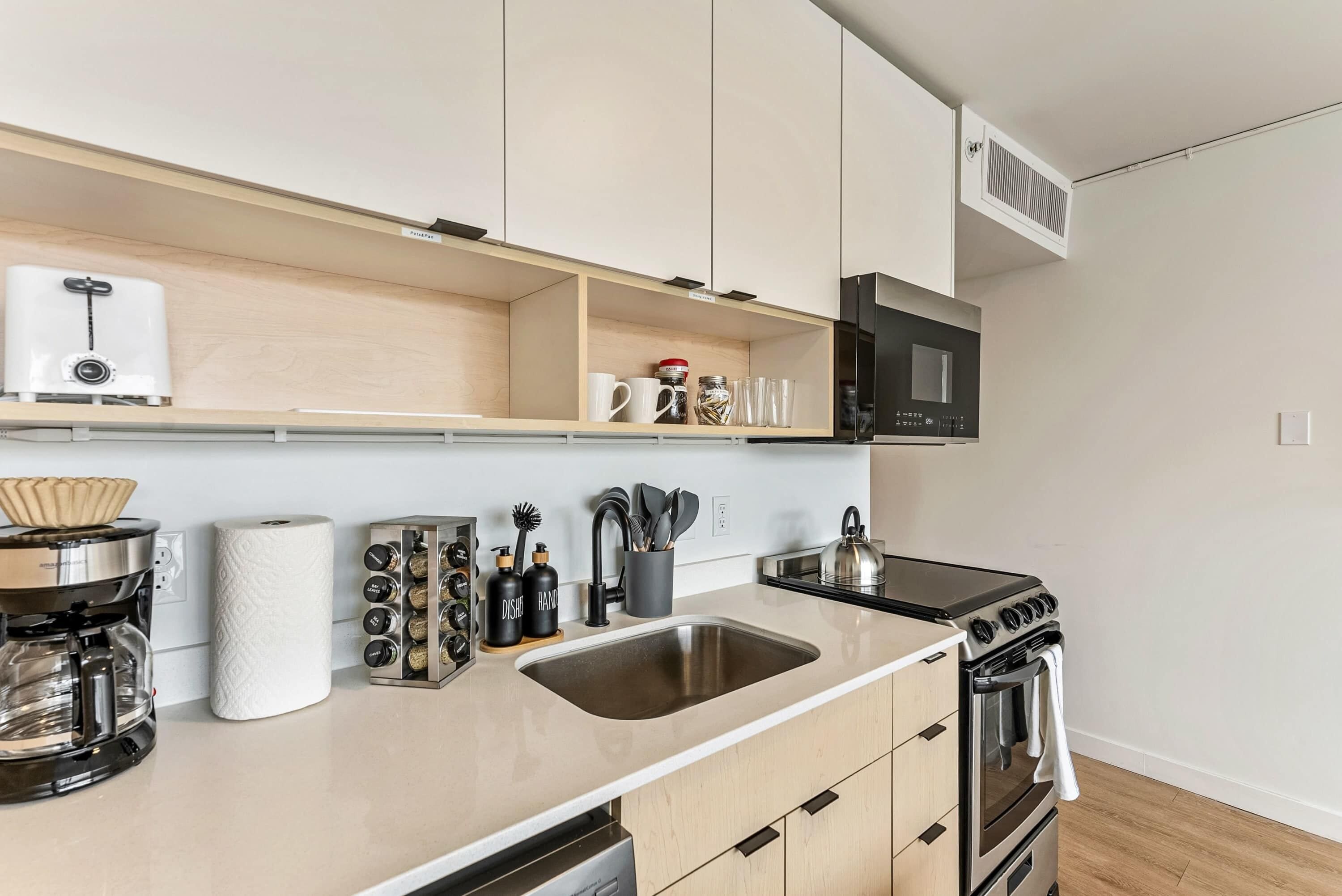 Une cuisine moderne équipée d’un évier en acier inoxydable, d’une machine à café, d’un four à micro-ondes et d’une cuisinière.