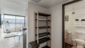 A modern apartment with a balcony, a compact bathroom, and a built-in shelving unit.
