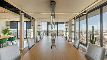 Una sala conferenze con un ampio tavolo, sedie e vista sulla città attraverso grandi finestre.