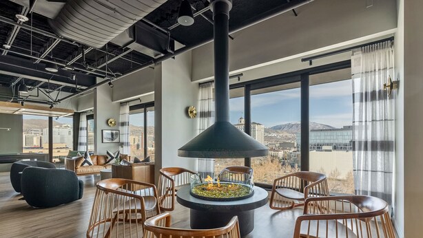 Ein modernes Wohnzimmer mit zentralem Kamin, großen Fenstern und Blick auf die Stadt.