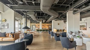 Ein großzügiges, modernes Interieur mit hohen Decken, freiliegenden Leitungen und einer Mischung aus Sitzbereichen, darunter Sofas und Sessel.
