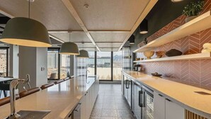 Eine moderne Küche mit einer langen Arbeitsplatte, Pendelleuchten und Blick auf die Stadt.