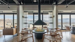 Ein modernes Interieur mit zentralem Kamin, einer Sitzecke und großen Fenstern mit Blick auf die Stadt.