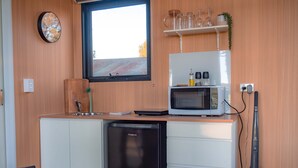 A compact kitchen with a microwave, dishwasher, and a window. - Coleslea by Tiny Away (Leeton)