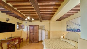 A bedroom with a wooden ceiling, a bed, a desk, and a chair.