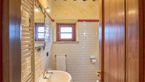 A bathroom with a wooden door, a white sink, a toilet, and a window.