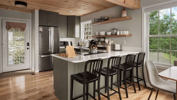 Een moderne keuken met een centraal eiland, barstoelen en uitzicht op de omgeving.